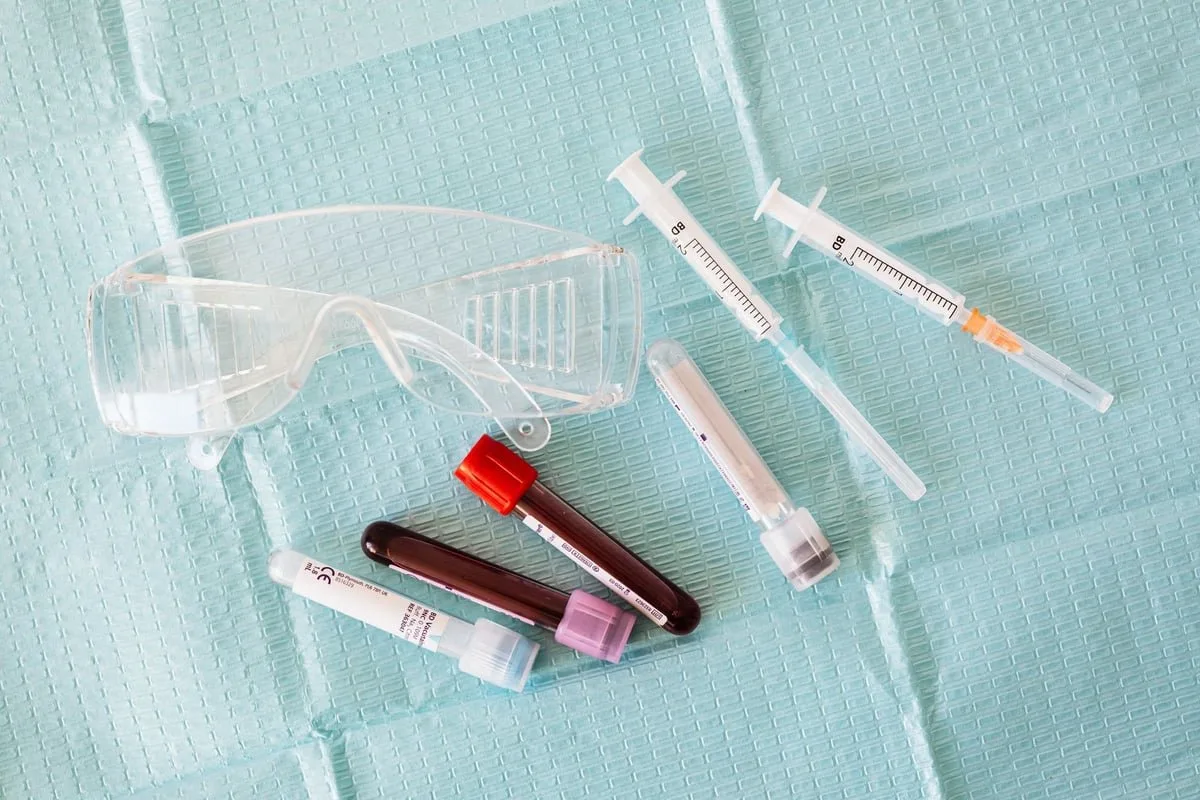 seringa e tubo de coleta de sangue sobre bancada de posto de saúde