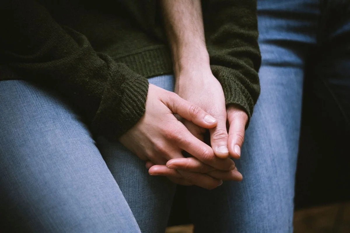 Mãos calejadas segurando um punhado de grãos colhidos em uma plantação