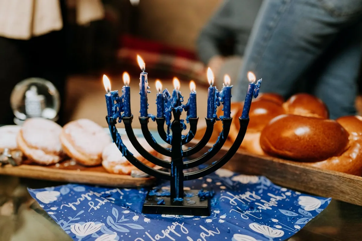 Candelabro judaico de sete bracos sobre mesa, ao lado de livro de oracoes
