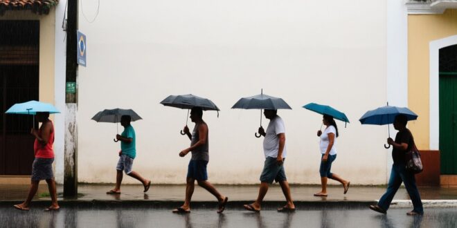 Pessoas caminham com guarda-chuvas em calçada molhada, sob chuva, em rua de cidade brasileira
