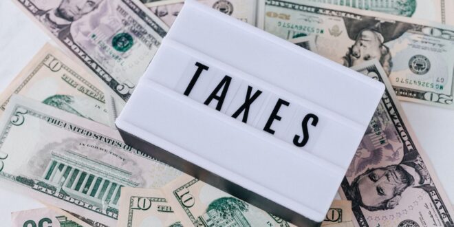 Caixa de luz retrô branca com TAXES sobre notas de dólar, símbolo de rendimentos e trabalho