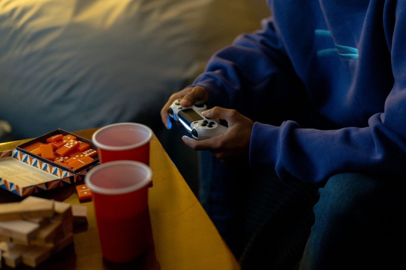 Pessoa aproveitando uma sessão de jogos com console e lanches em ambiente fechado