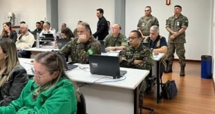 Militares em uniforme camuflado sentados em sala de aula diante de um notebook