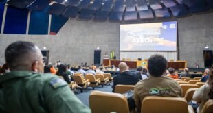 Plateia em auditório assiste a palestra com telão exibindo avião do evento Aerofire