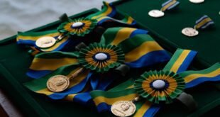 Medalhas douradas com fitas verde-amarelas dispostas em bandeja de veludo verde
