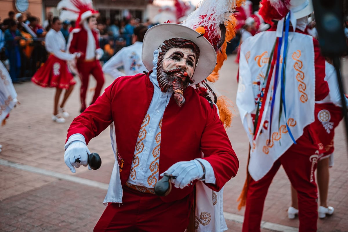 Grupo de maracatu com tambores e indumentária colorida se apresenta em desfile cultural