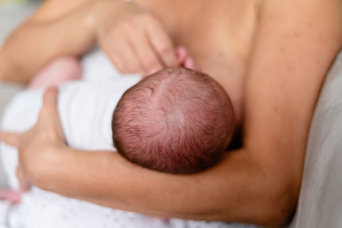 Mãe amamentando bebê recém-nascido em enfermaria de maternidade