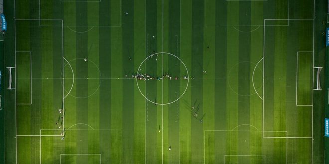 Atleta em campo esportivo durante treino, com bola aos pés