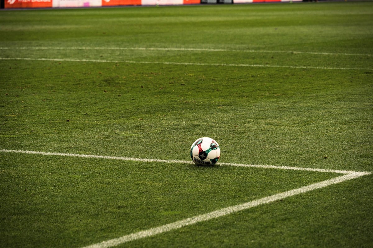Bola de futebol sobre o gramado de um campo vazio