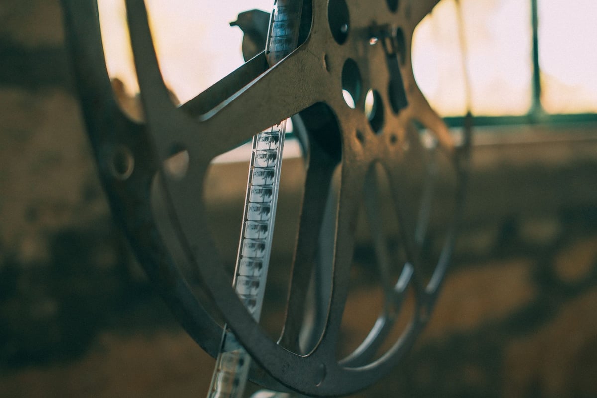 Rolo de filme antigo ao lado de projetor de cinema vintage sobre mesa