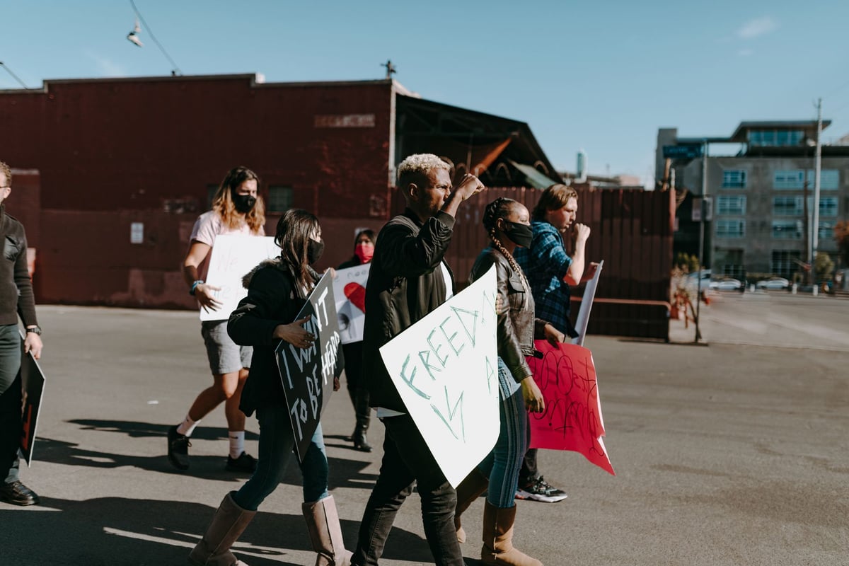 Mãos segurando cartaz de campanha contra o tráfico de pessoas em manifestação de rua