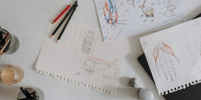 Mesa de trabalho com pranchetas, paleta de cores e materiais de design gráfico