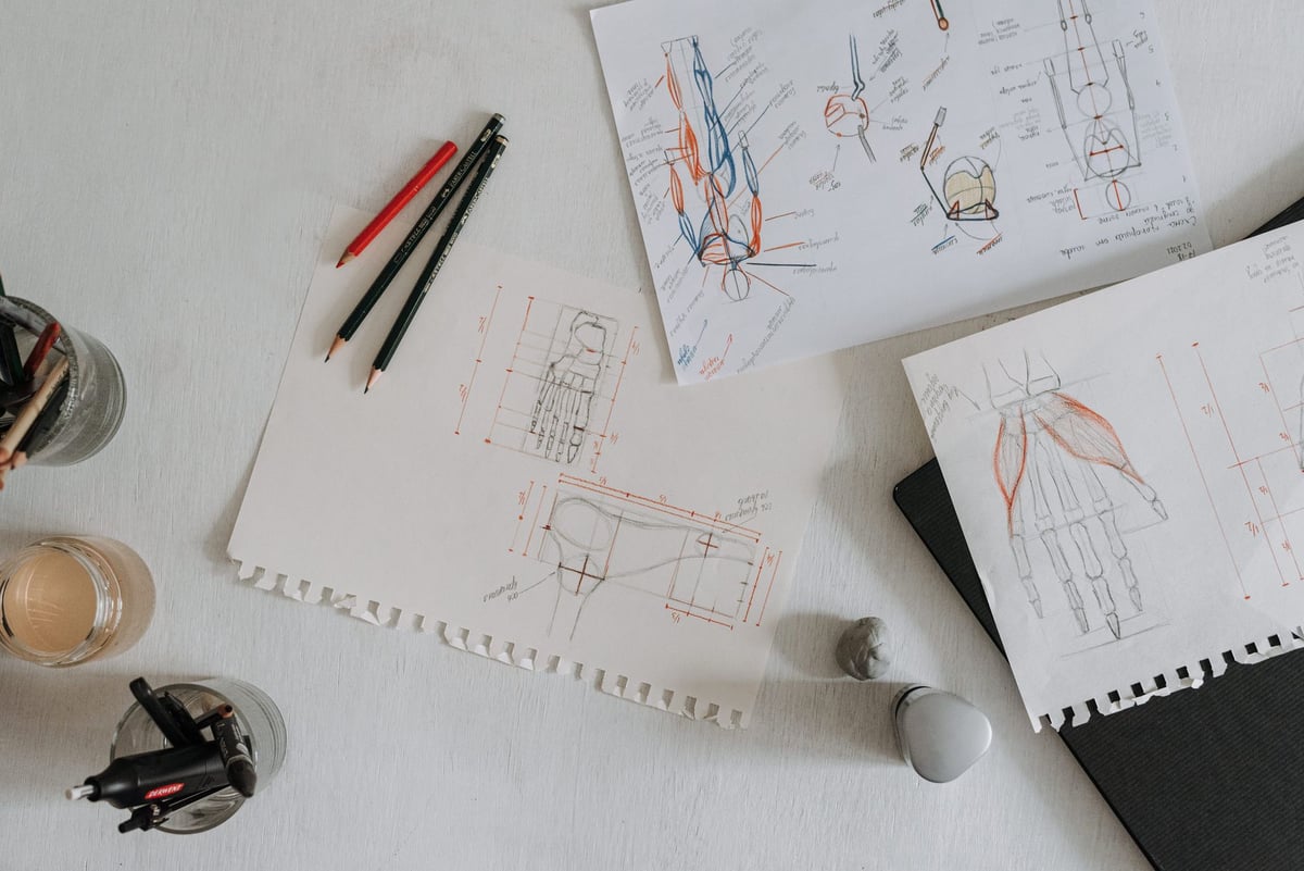 Mesa de trabalho com pranchetas, paleta de cores e materiais de design gráfico