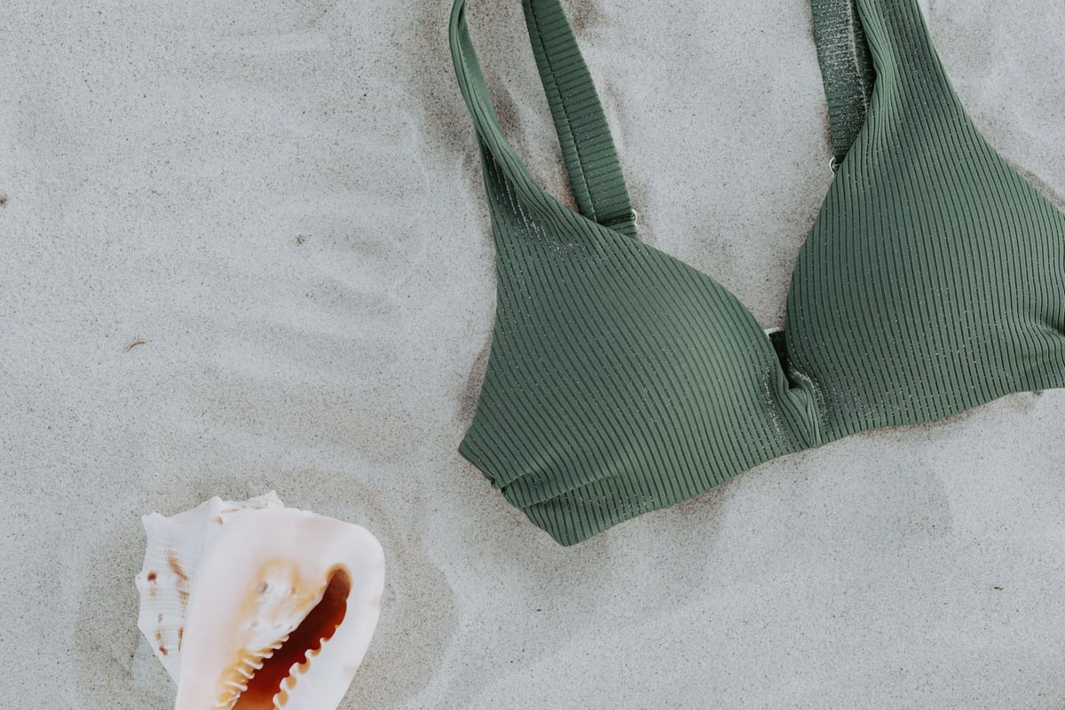 Biquíni estampado exposto sobre areia de praia com mar ao fundo