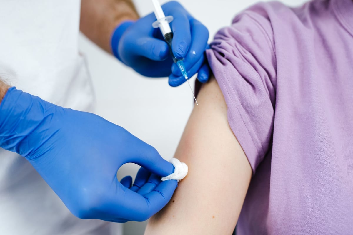 Profissional de saúde aplicando vacina no braço de paciente em posto de saúde
