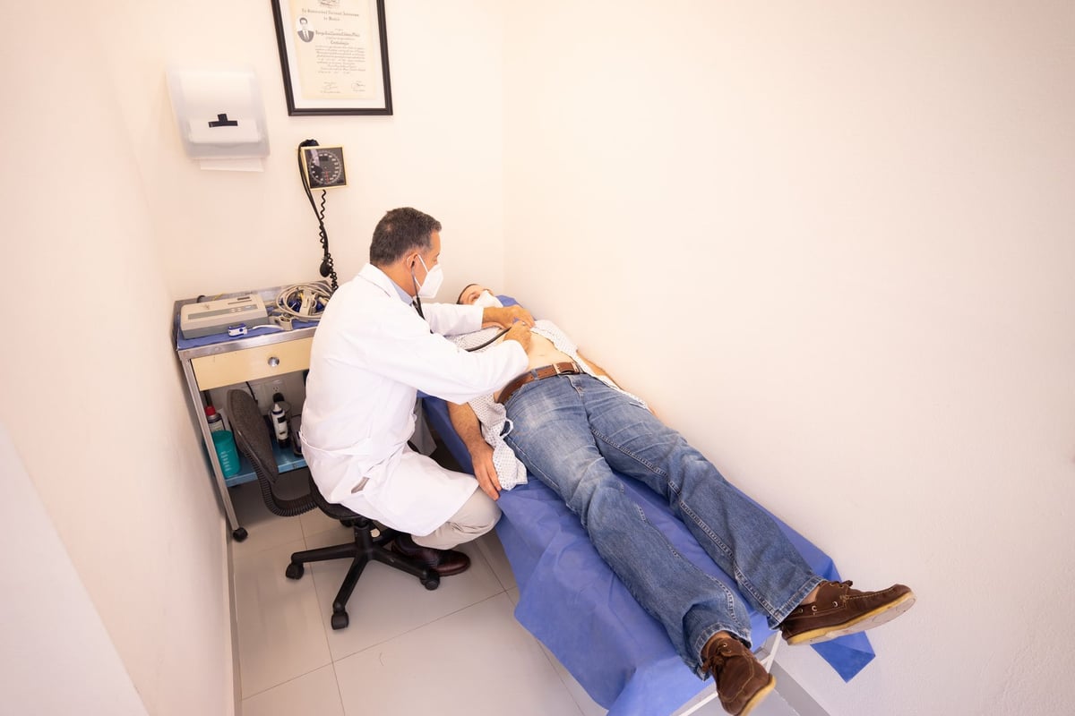 Médico auscultando o pulmão de um paciente jovem em consultório de pneumologia