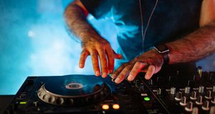 DJ manuseia mesa de som e toca-discos em cabine durante festa noturna