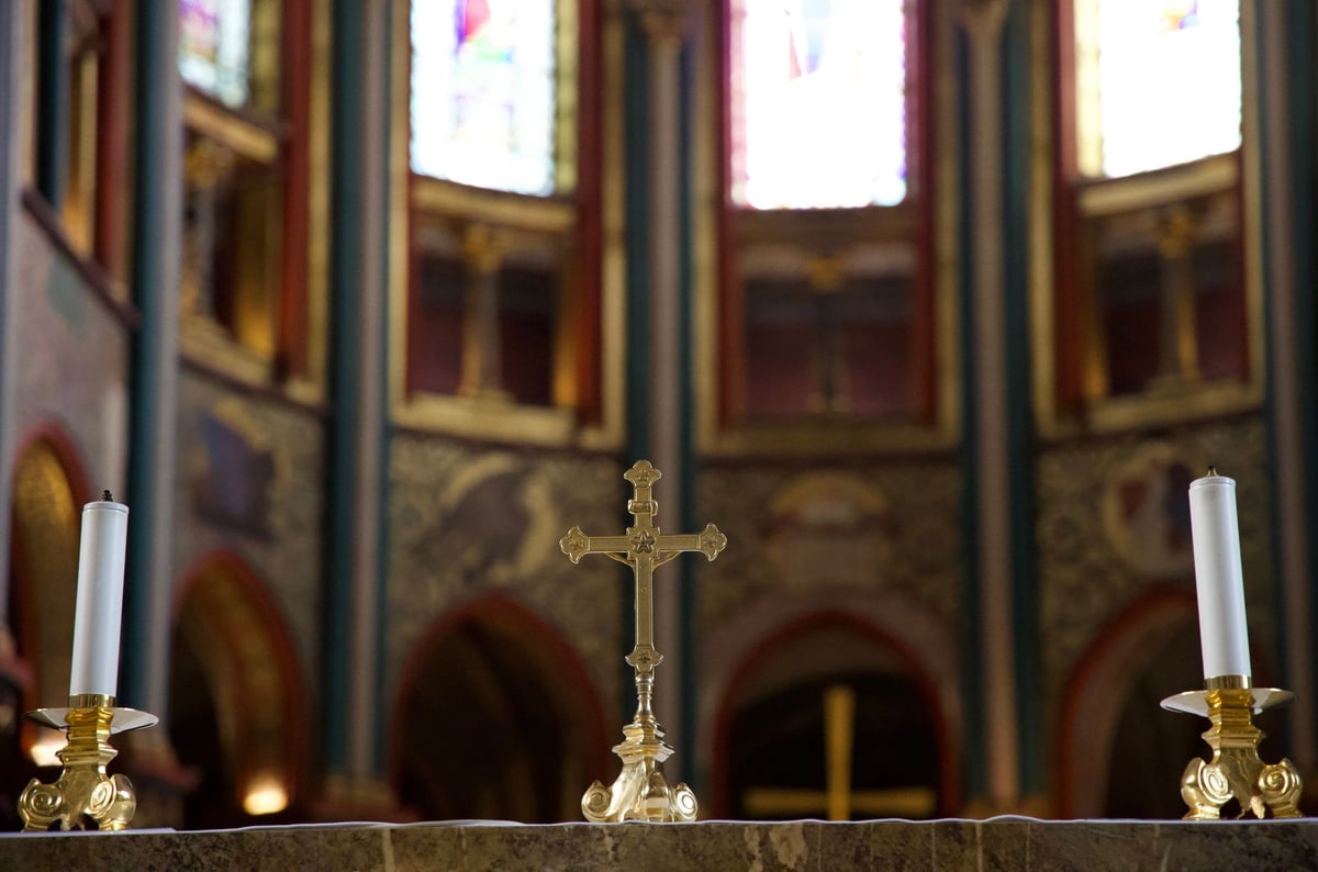 Livro antigo aberto sobre altar de igreja ao lado de vela acesa