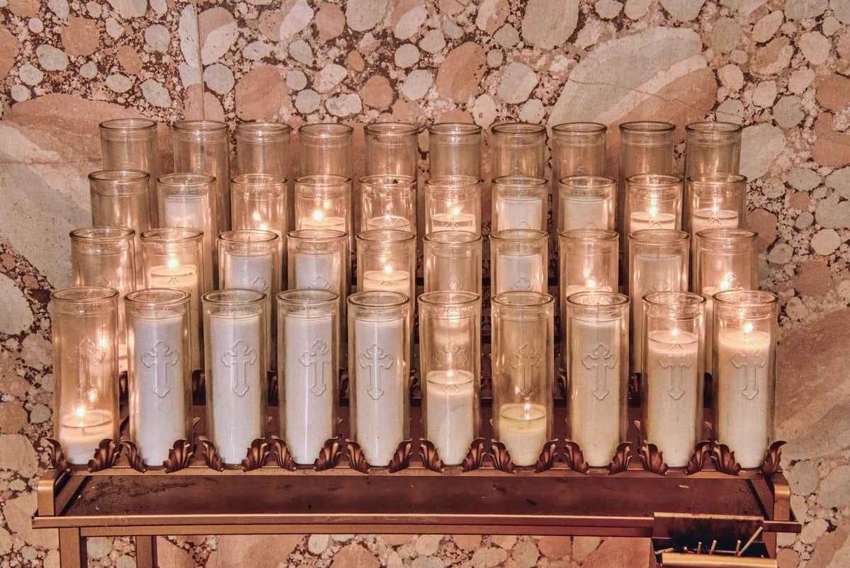 Imagem de santo com flechas em altar de igreja, iluminada por velas acesas