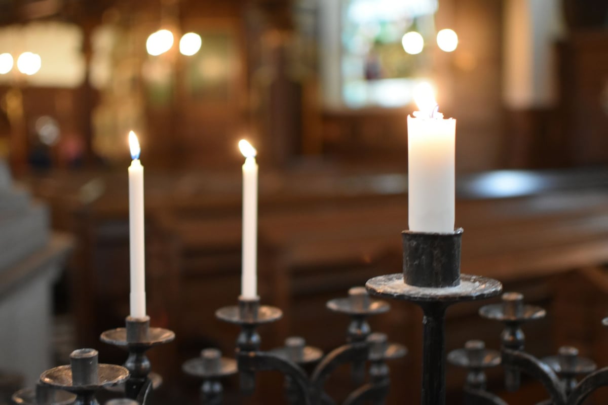 Mesa posta com toalha branca, pratos e velas acesas para uma ceia em família