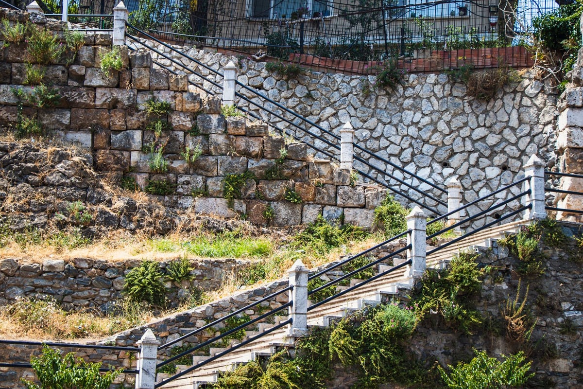 escadaria de pedra lotada de romeiros subindo um morro ao entardecer