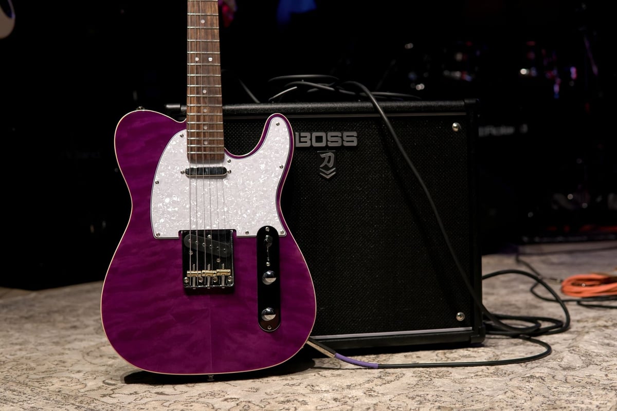 Guitarra elétrica apoiada em um amplificador com luzes de palco ao fundo