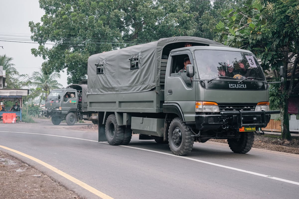 Coluna de veículos militares antigos avançando por estrada em preto e branco