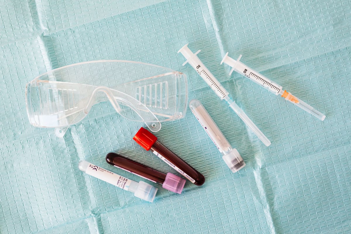 seringa e tubo de coleta de sangue sobre bancada de posto de saúde