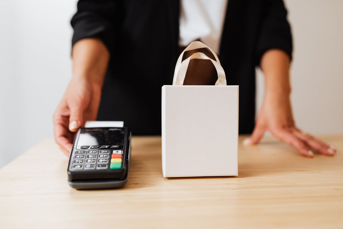 vendedora entregando sacola de compras para cliente em loja