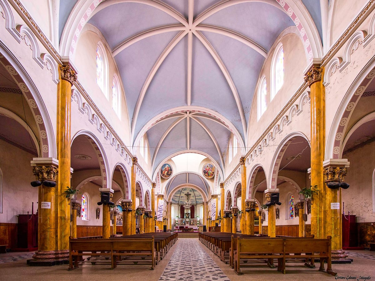 Interior vazio de igreja antiga, bancos de madeira e luz entrando pelas janelas