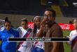 pênaltis: Homem de óculos e casaco marrom fala para grupo de mulheres em uniforme de futebol em campo com publicidade