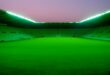 Estádio de futebol vazio com gramado iluminado pelos refletores ao anoitecer