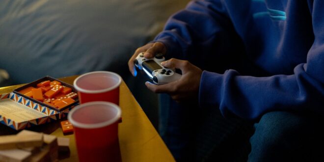 Pessoa aproveitando uma sessão de jogos com console e lanches em ambiente fechado